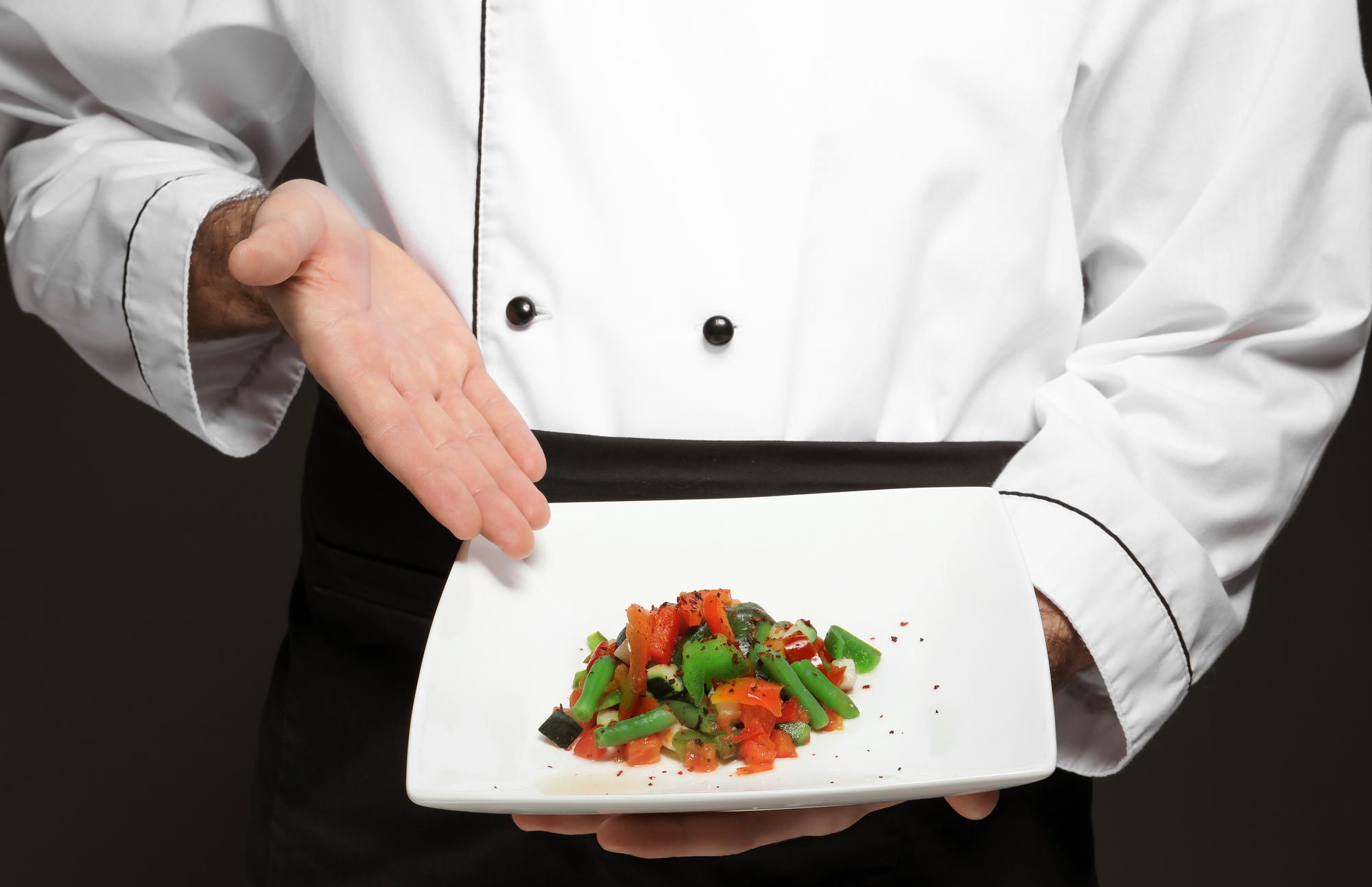 Chef presenting plated dish in elegant kitchen
